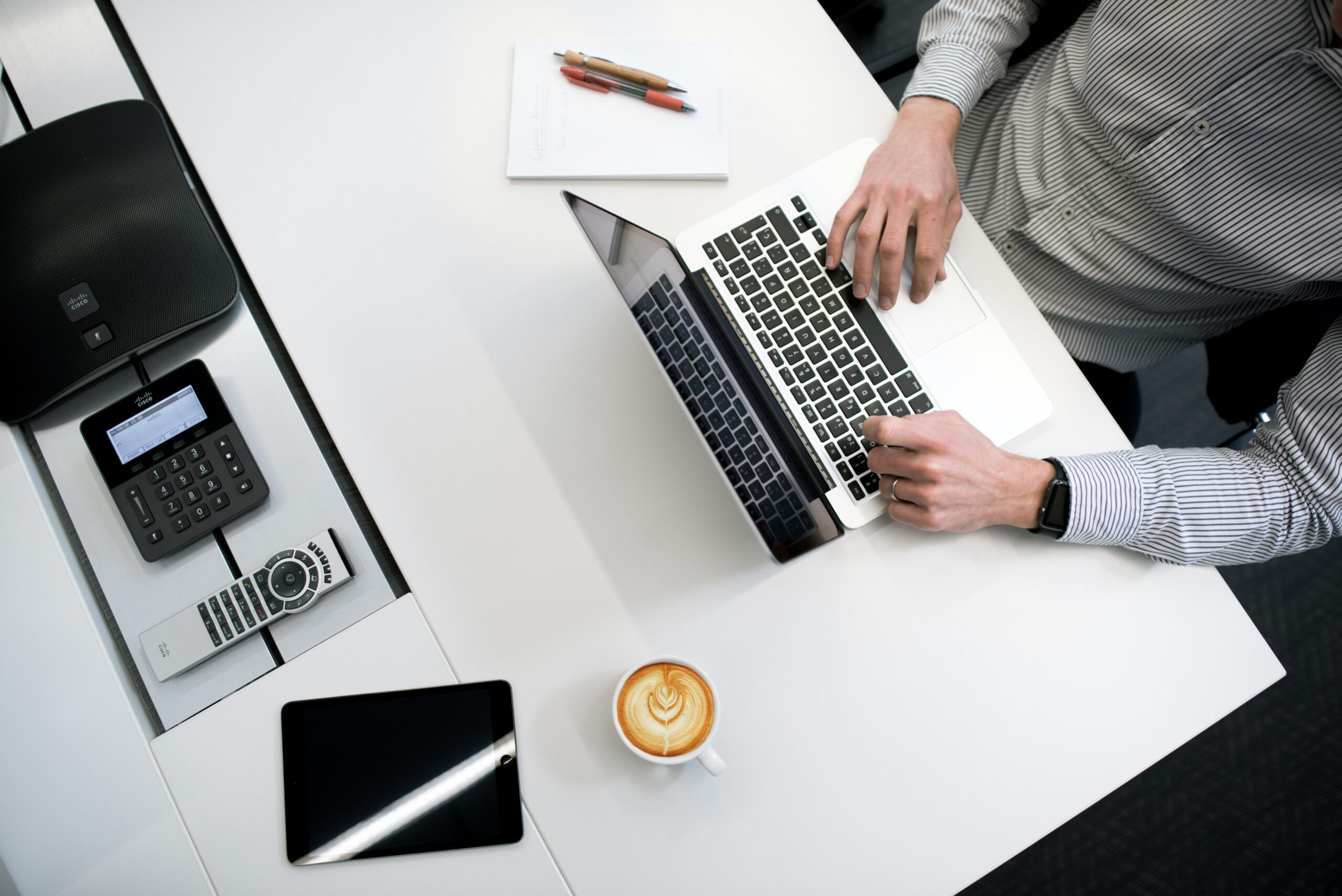 Man sitting on a desk typing on a laptop keyboard