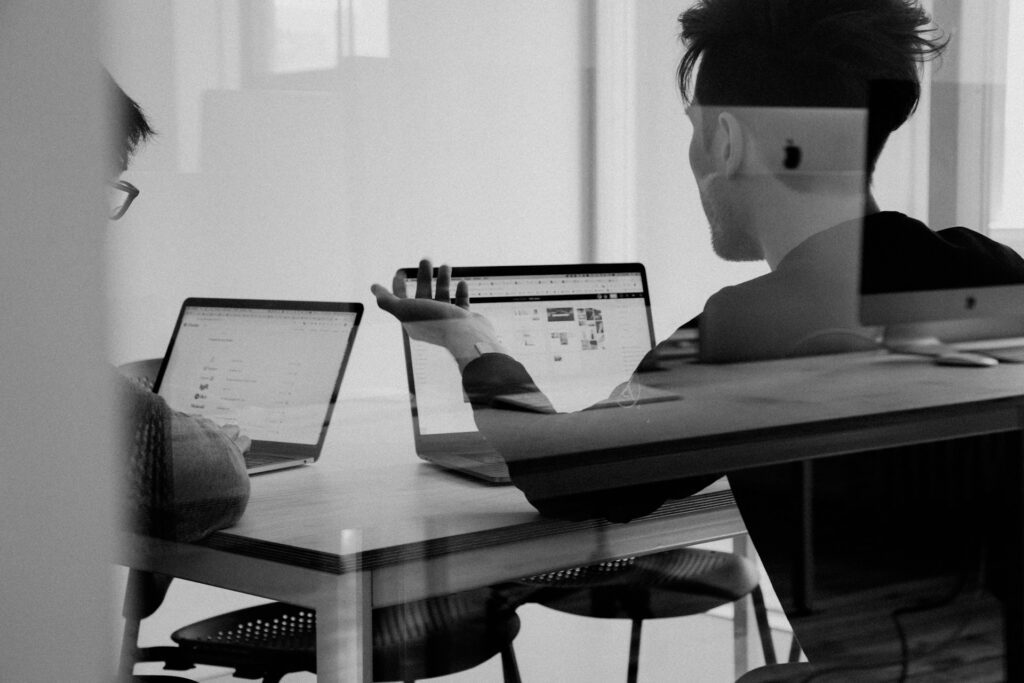 people sitting on a desk with laptops